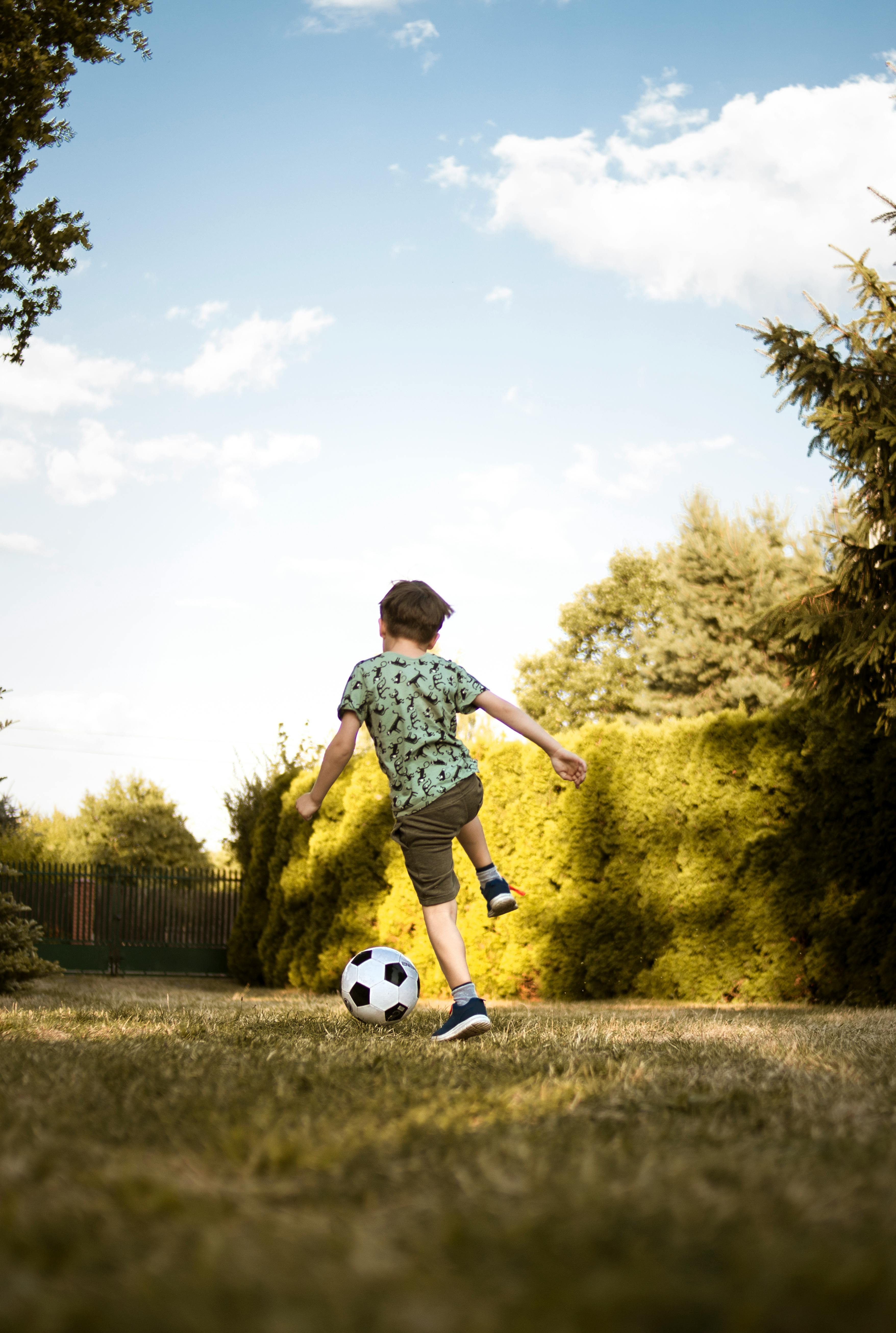 Low-Angle Photo of a Boy Playing Soccer