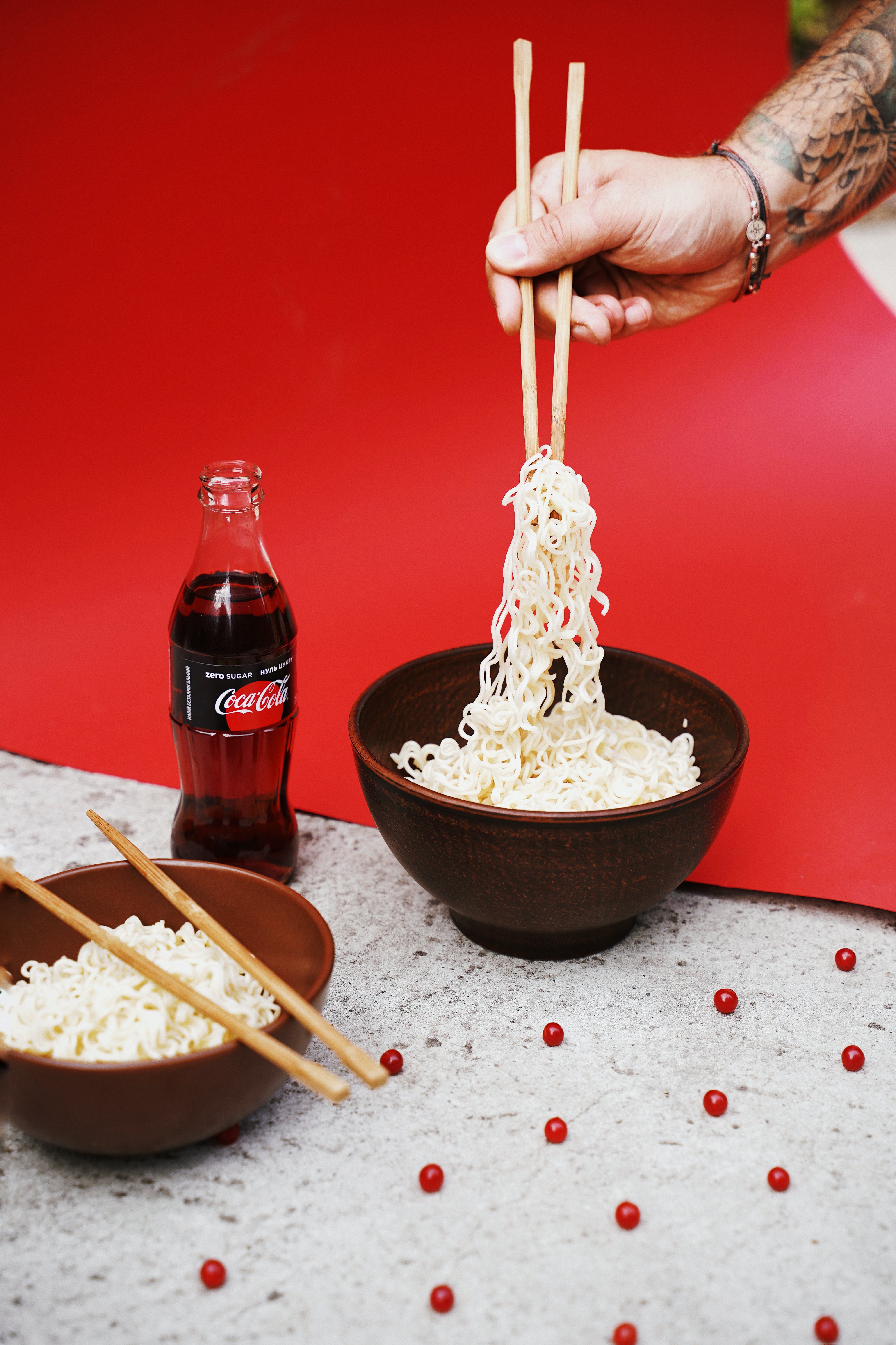 Person Lifting Noodles from Ceramic Bowl With Wooden Chopsticks